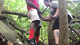 A Caucasian woman performs oral sex on an African-American man in a forest